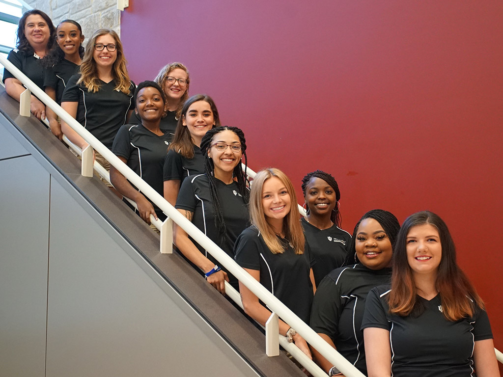 A group of student orientation leaders posing for a photo on a staircase.