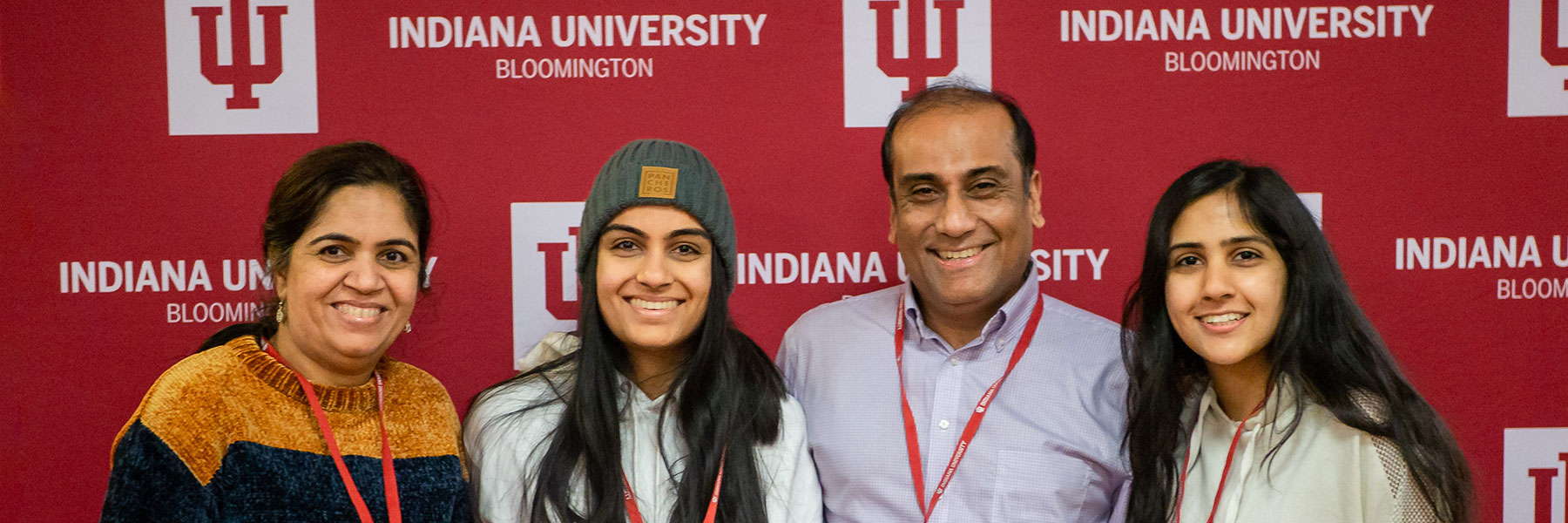 A family poses in front of an IU backdrop.